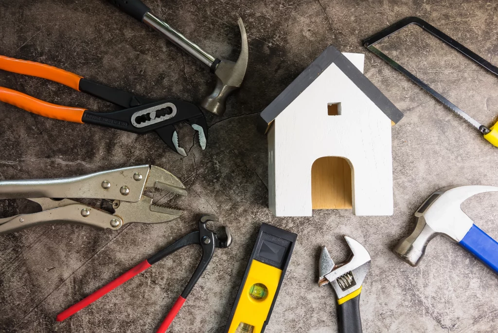 Werkzeuge liegen im Kreis um ein Holzhaus